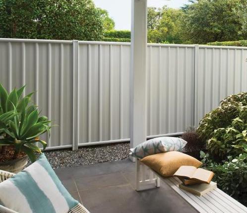 Cream Colorbond steel fence enclosing a poolside area with gravel and planting
