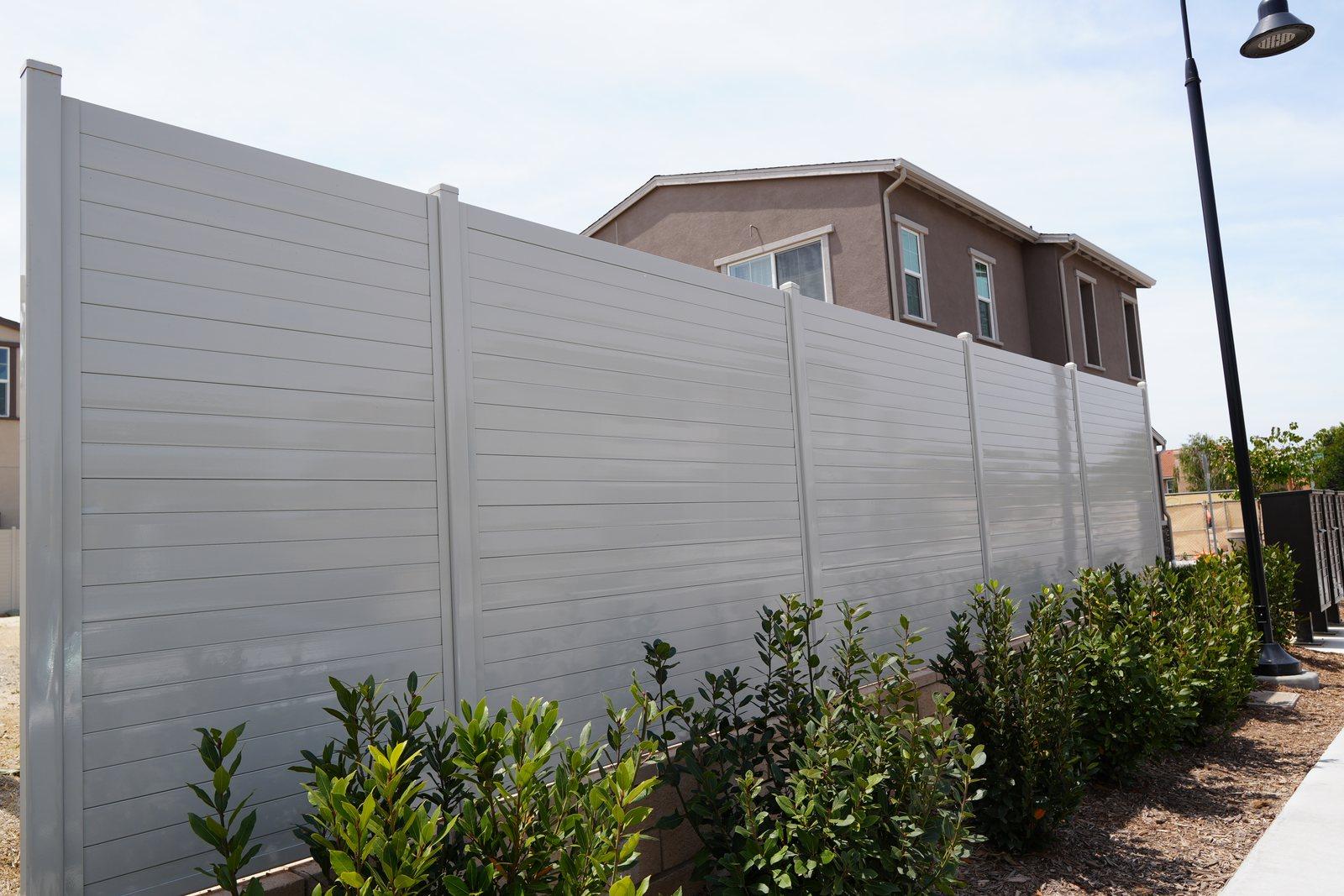 Ribbed steel privacy fence with low planting kept back from the base, Santa Paula