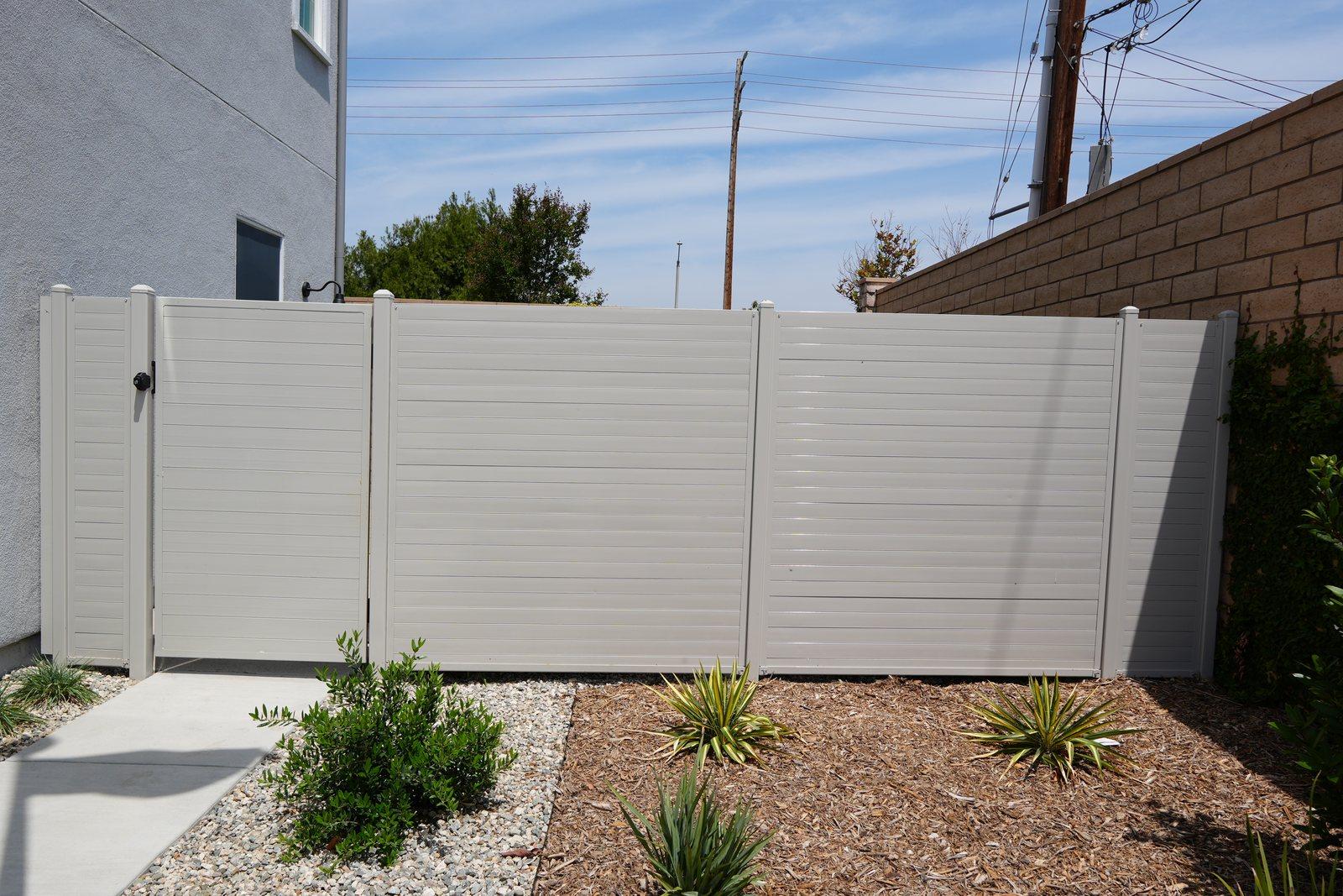 Ribbed steel privacy fence and matching gate along a walkway in Santa Paula